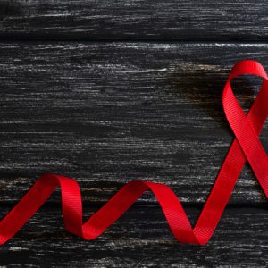 closeup-red-ribbon-awareness-on-black-wooden-table-background-for-world-aids-day-campaign_53476-2810